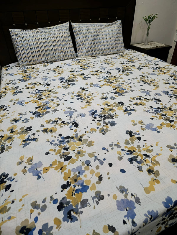 Floral patterned bedspread on a bed with striped pillows.