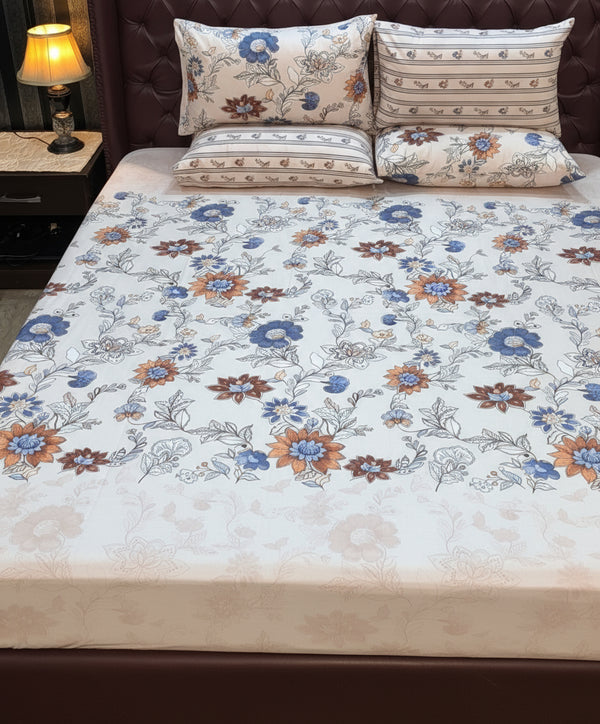 Cream floral bedding set with blue and orange flowers on a bed